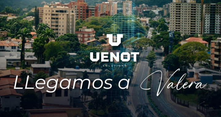 Esta es una imagen a vista de pájaro de la ciudad de Valera, en el estado Trujillo de Venezuela. Se aprecian numerosas casas de techos rojos en primer plano, seguidas por una franja de vegetación y una avenida principal que atraviesa la ciudad. Al fondo, se elevan imponentes montañas verdes que enmarcan la escena urbana. La imagen destaca el desarrollo de la ciudad en medio de un entorno natural montañoso. El cielo está nublado.