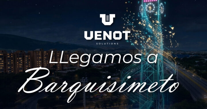 Una toma aérea nocturna que muestra un paisaje urbano con edificios de apartamentos de ladrillo a la izquierda y montañas al fondo. En el centro-derecha, una gran torre de reloj holográfica está hecha de líneas de luz azul cyan entrelazadas, con un reloj digital y una pantalla de texto en la parte superior, rodeada por una espiral de partículas de luz doradas y fragmentos. Un parque y carreteras están en el primer plano.