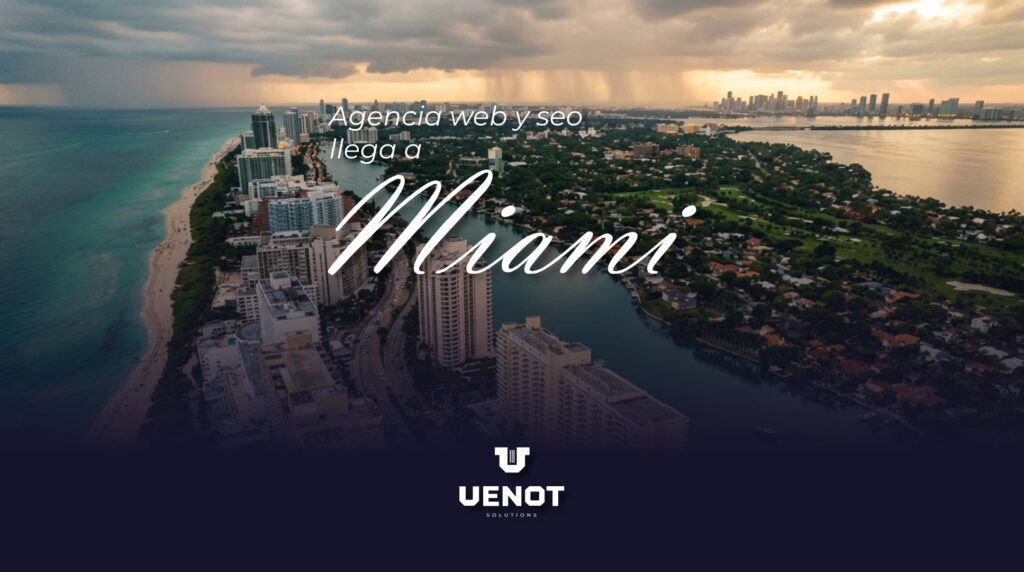 Vista aérea de Miami Beach y el horizonte de Miami al atardecer, con una playa turquesa a la izquierda y un canal navegable a la derecha. Superpuesto en el centro hay un texto blanco que dice: 'Agencia web y seo llega a Miami', con 'Miami' en una tipografía cursiva grande. En la parte inferior, sobre un fondo oscuro, se encuentra el logotipo de VENOT Solutions".